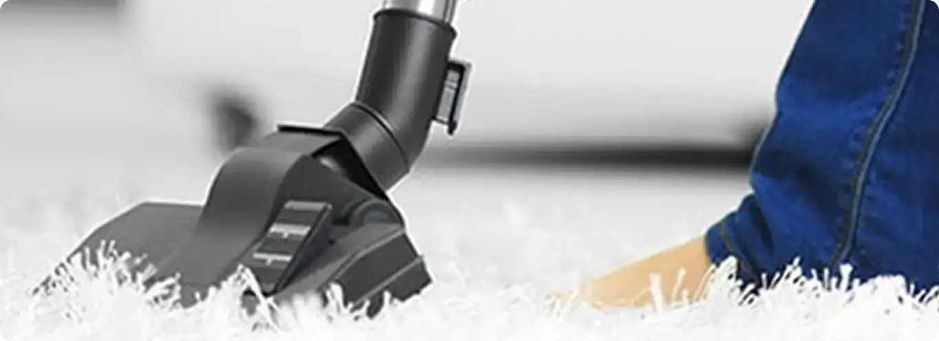 Close-up of a professional vacuuming a white carpet in Fort Bliss.