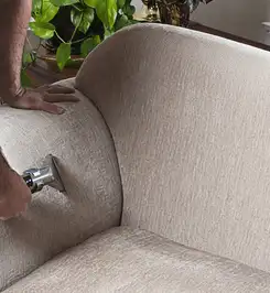 Professional upholstery cleaner deep-cleaning a fabric sofa with a handheld extraction tool and hose El Paso, TX.